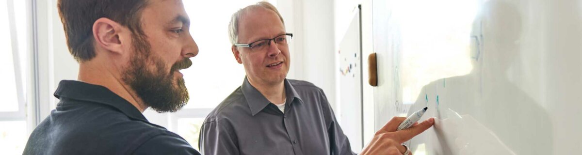 Two microscopists in discussion at a whiteboard
