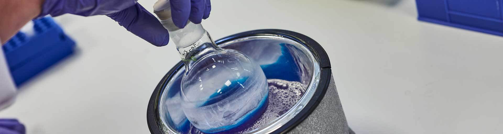 Close-up of a scientist putting a flask with colorful content in a larger container